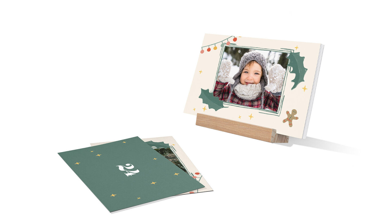 Tarjetas CEWE en un soporte de madera, rodeadas de elementos festivos.