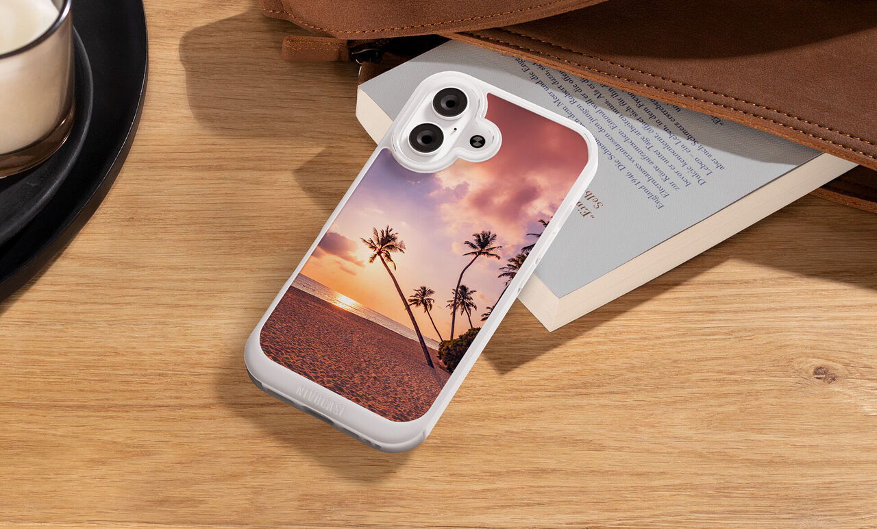 Funda de móvil personalizada con fotos Nivocase. Foto de unas palmeras en la playa, apoyada sobre un libro en la carcasa.